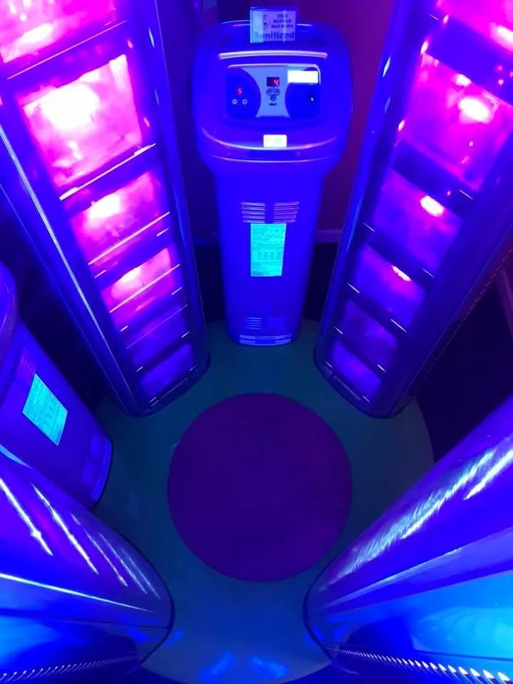 Inside a stand-up tanning booth, lit violet and blue